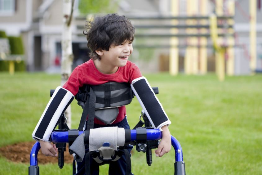 صبي صغير لا يستطيع المشي بسبب تعرضه للشلل ويقوم بالاستعانة بأجهزة طبية مساعدة تحيط بجسمه لتساعده على المشي
