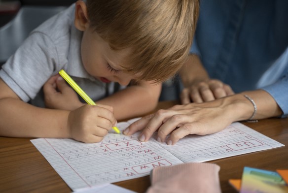 طفل أشقر يكتب أحرف باللغة الإنكليزية على الدفتر