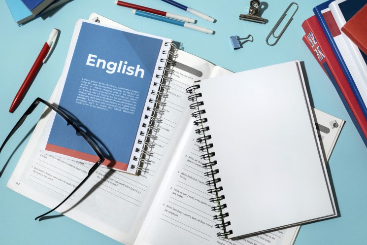 كتب ودفتر مكتوب عليه بالإنكليزية English وأقلام ونظارة طبية