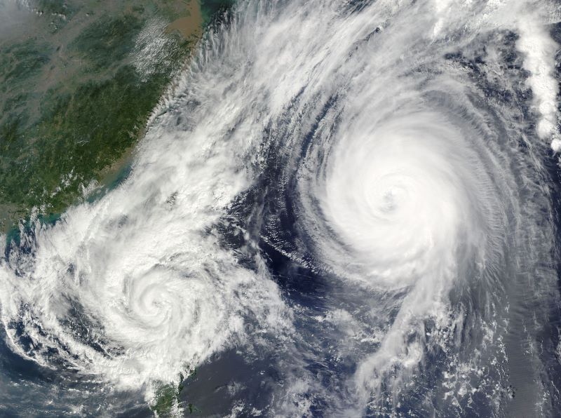 صورة جوية لمجموعتين ضخمتين من الغيوم البيضاء التي تلتف حول بعضها لتشكل إعصارين بجانب بعضهما البعض